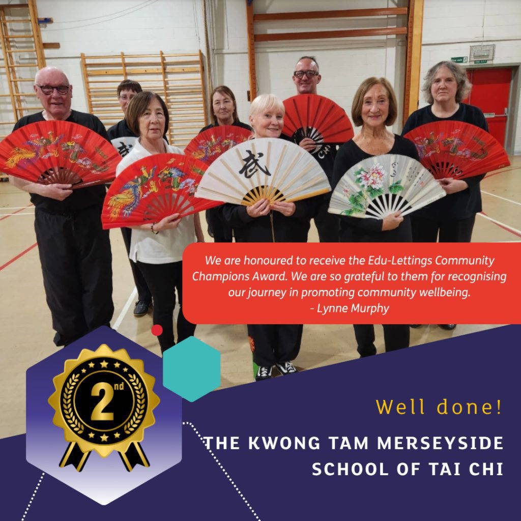 Members of the Kwong Tam Merseyside School of Tai Chi holding colourful fans in a sports hall after winning second place in the Edu-Lettings Community Champions Competition 2025. Quote from Lynne Murphy reads: “We are honoured to receive the Edu-Lettings Community Champions Award. We are so grateful to them for recognising our journey in promoting community wellbeing.”